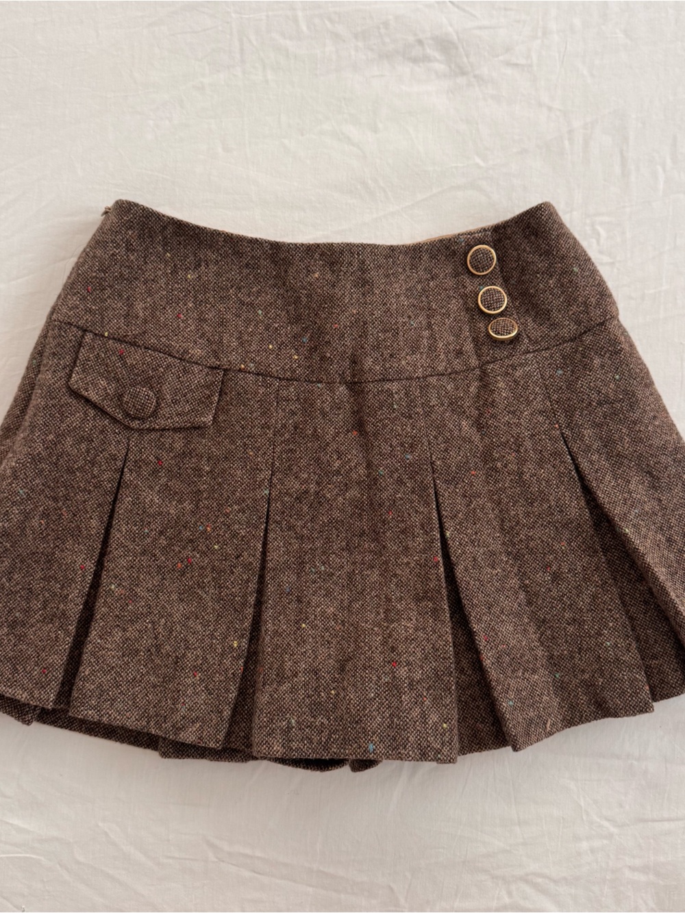 Brown pleated wool mini skirt with pockets and button detail. Size: S